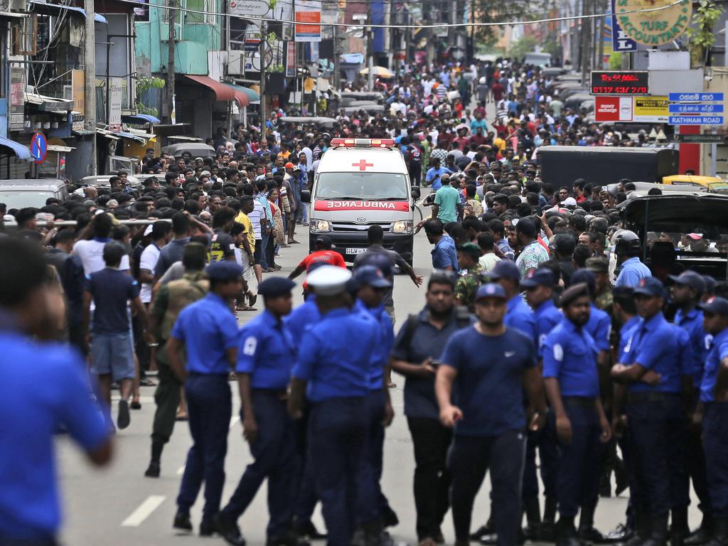 Sri Lankan police officers clear the road as an ambulance drives through carrying injured of Church blasts in Colombo, Sri Lanka. Picture: AP