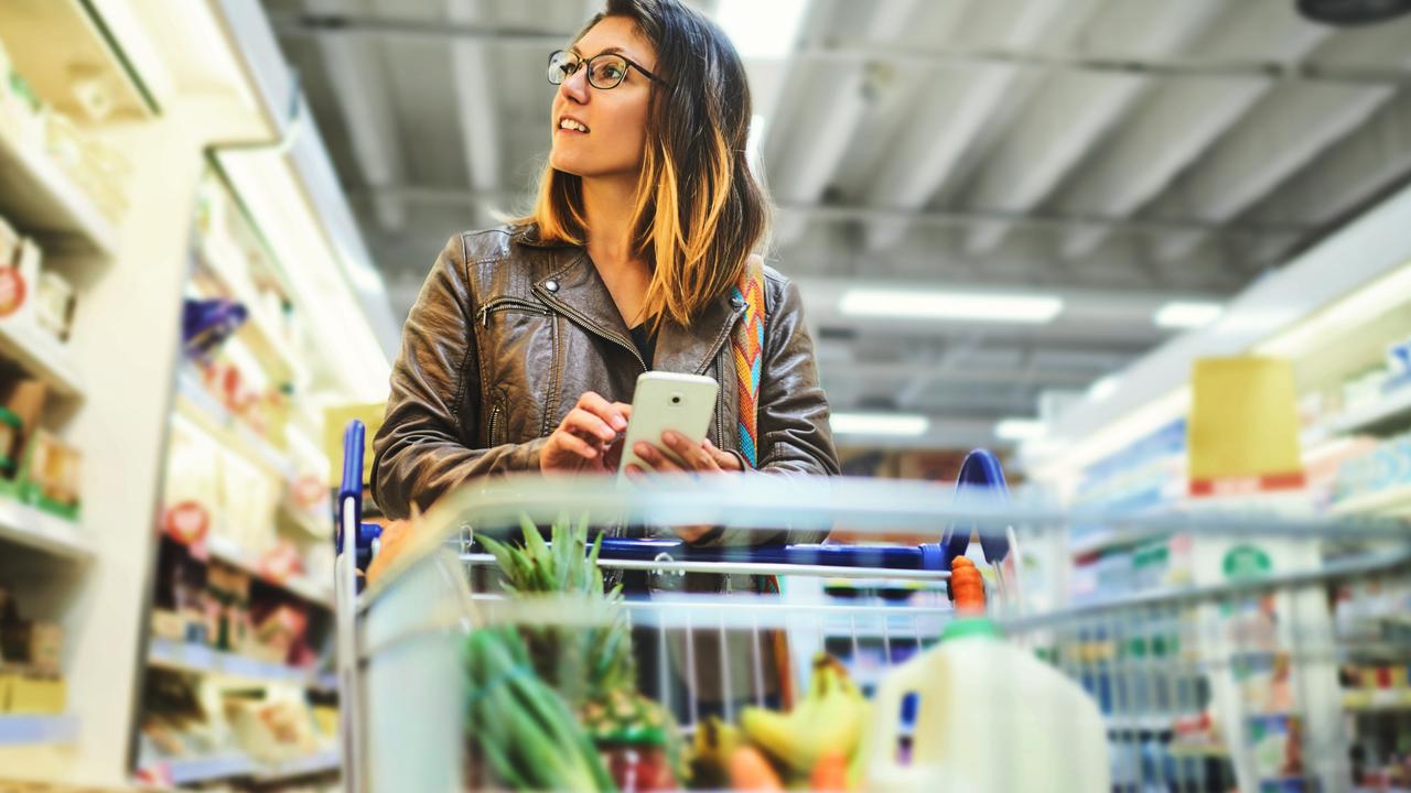 Shot of a young woman using a mobile phone in a grocery store