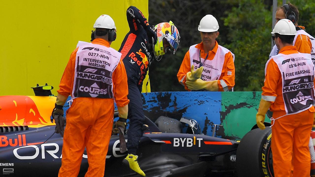 Track marshals watch as Red Bull Racing's Mexican driver Sergio Perez climbs out of his car after crashing into a barrier at the start of the first practice session at the Hungaroring race track in Mogyorod near Budapest on July 21, 2023, ahead of the Formula One Hungarian Grand Prix. (Photo by Ferenc ISZA / AFP)