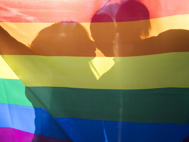 people, homosexuality, same-sex marriage, gay and love concept - close up of happy lesbian couple holding rainbow flag