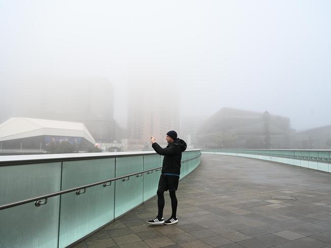 29.7.23 - Fog around Adelaide CBD. Adam Gardnir on the Oval footbridge.  Picture: Naomi Jellicoe