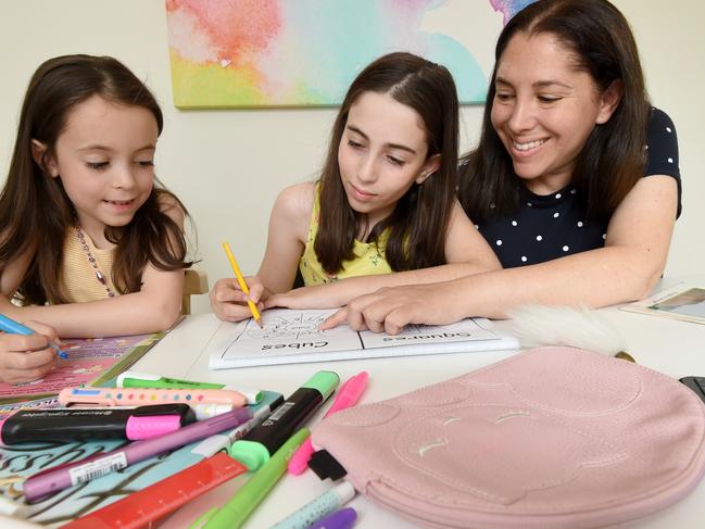 Cindi Sommers helping her daughters Bianca (6) and Amy (11) study at home after pulling them out of school. Picture: Tony Gough