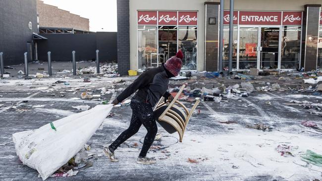 A suspected looter pulls a few items along the ground outside a vandalised mall in Vosloorus, on the outskirts of Johannesburg. Photo: AFP