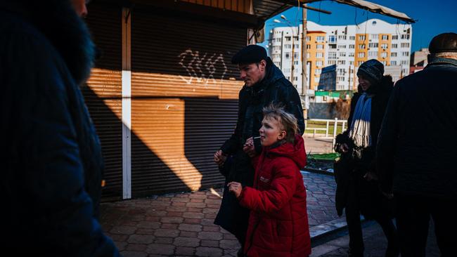 A man strolls his children in Kherson where two recently were injured in missile strikes.