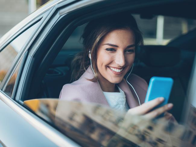 Young woman on the back seat with smart phone and headphones