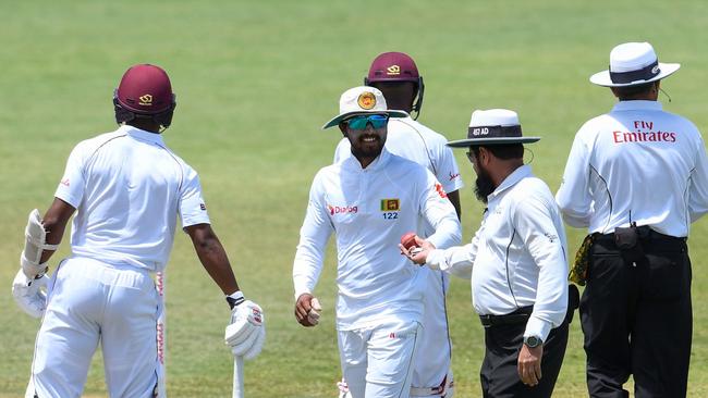 Dinesh Chandimal (C) laughs as umpire Aleem Dar checks the ball. Picture: AFP