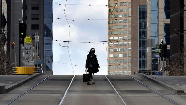 A woman crosses a deserted Collins St in Melbourne. Picture: David Geraghty