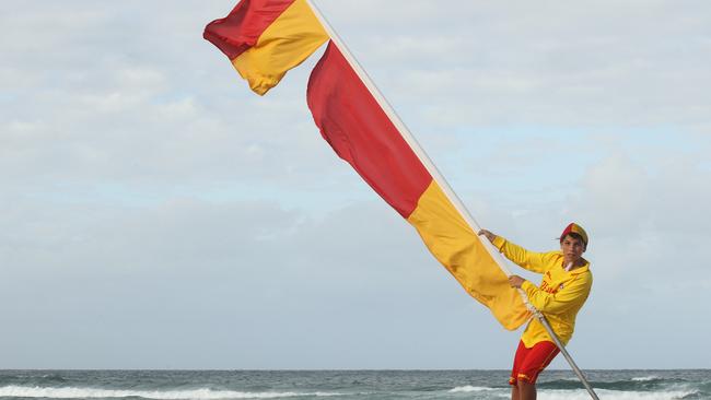 Burleigh Surf Life Saving member struggles to put up the red and yellow flags due to the strong southerly winds.