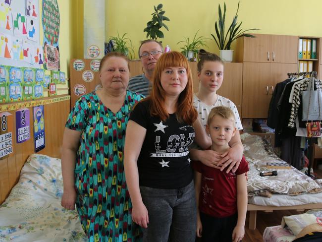 Mariia*, 13 with her mother Olena*, brother Mykyta*, 6, and grandparents Irina* and Myron* stand in the classroom where they are living. Picture: Kimberley Gardiner.