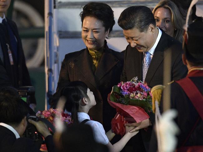 China's President Xi Jinping  (C-R) receives a present, next to China's First Lady Peng Liyuan (L), upon their arrival at Ezeiza International airport in Buenos Aires province, on November 29, 2018. - Global leaders gather in the Argentine capital for a two-day G20 summit beginning on Friday likely to be dominated by simmering international tensions over trade. (Photo by Juan Mabromata / AFP)