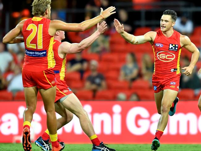 Ben Ainsworth (centre) of the Suns celebrates kicking a goal with the mates during the AFL Marsh Community Series pre-season match between the Gold Coast Suns and Geelong Cats at Metricon Stadium on the Gold Coast, Saturday, February 22, 2020. (AAP Image/Darren England) NO ARCHIVING, EDITORIAL USE ONLY