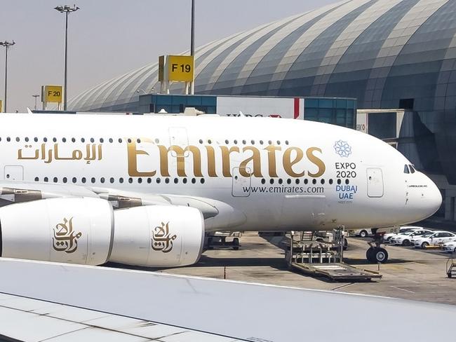 Dubai, UAE - August 9, 2015: As one Emirates Airbus A380 departs busy Dubai Airport, a similar aircraft in the next bay (F19) is framed in the passenger window as it is being prepared for its next flight.