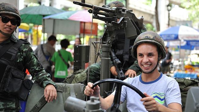 A foreign tourist sits in a Thai Army vehicle as soldiers deploy on a Bangkok street. Pic