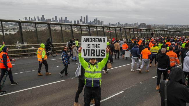 A protester holds a placard as thousands march through after Victorian government announces construction shutdown on September 21, 2021. Picture: Getty Images