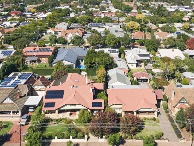 Elevated view of houses & rooftops in leafy eastern suburb of Adelaide during the transition from summer to autumn: sunny with autumn leaf colours. Note the many solar panels installed on the rooftops providing power generation for the city.