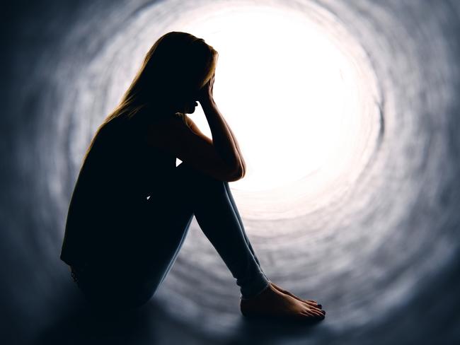 A depressed woman sitting alone is a dark tunnel with light at the other end.