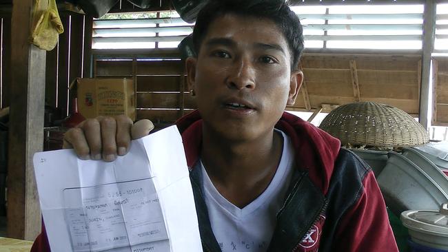 Maung Soe of Myanmar holds up a copy of the seafarer's book given to him before he boarded a Thai fishing trawler, in Benjina, Indonesia. Illegal workers are given false documents because Thai boats cannot hire undocumented crew. 