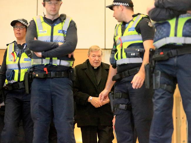 Police officers circle Cardinal George Pell as he arrives at the Melbourne Magistrates’ Court. Picture: Mark Stewart