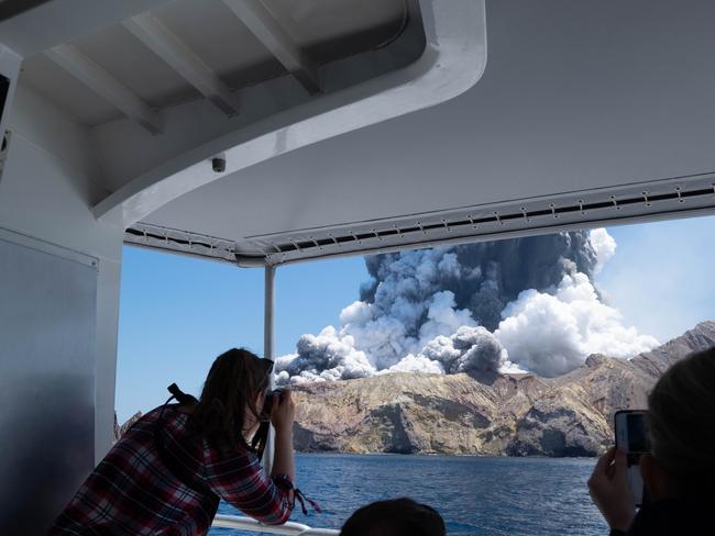 Tourists on a boat look at the eruption of the volcano on White Island. Picture: Michael Schade via AP