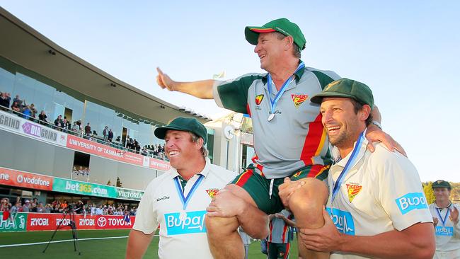 Mark Cosgrove and Ben Hilfenhaus carry Tim Coyle from the field as Tasmania celebrates winning the Sheffield Shield cricket final against Queensland at Blundstone Arena.