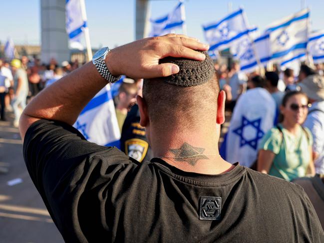 TOPSHOT - A man adjusts his kippah (Jewish skullcap) as right-wing Israelis demonstrate next to the Sde Teman military base near Beersheba, against the detention for questioning of military reservists who were suspected of abuse of a detainee following the October 7 attack in Israel, on July 29, 2024. The military said it has opened an investigation into the "suspected abuse" of a detainee at the Sde Teiman base set up for holding Palestinians arrested in Gaza since the war broke out. (Photo by Menahem Kahana / AFP)