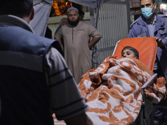 Paramedics help a Palestinian child injured following Israeli an air strike. Picture: Said Khatib / AFP