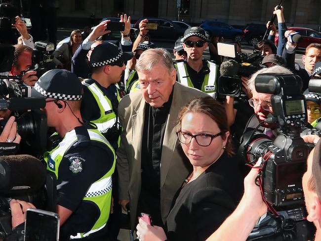 Cardinal George Pell flanked by police and media outside the Melbourne County Court last month. Picture: Getty