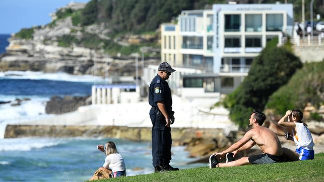 A NSW police officer asks people to move on while patrolling Sydney’s Bondi Beach over the Easter long weekend. Picture: AAP