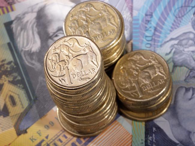 Three stacks of Australian one dollar coins on a background of bank notes. Shallow depth of field focus on tallest stack., cash money generic