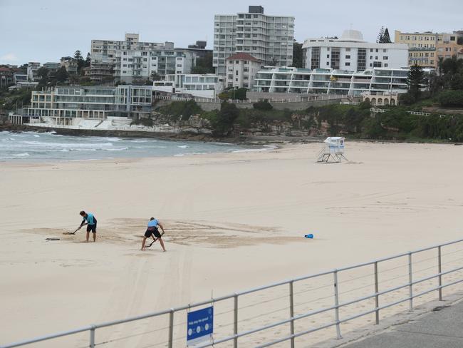 Bondi Rescue Lifeguards on Bondi Beach writing #stayhome in the sand, on the first morning of new restrictions to help limit the spread of COVID-19. Picture Rohan Kelly