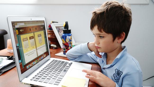 Juggling act … Phoenix Crawford does school work on a laptop while being homeschooled by his mum (who is also working from home) in Sydney last week. Picture: supplied