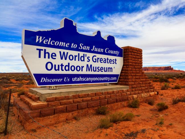 Monument Valley, Utah - November 1, 2016: The colorful Welcome to San Juan County sign with the natural beauty of the red sandstone buttes in the background.