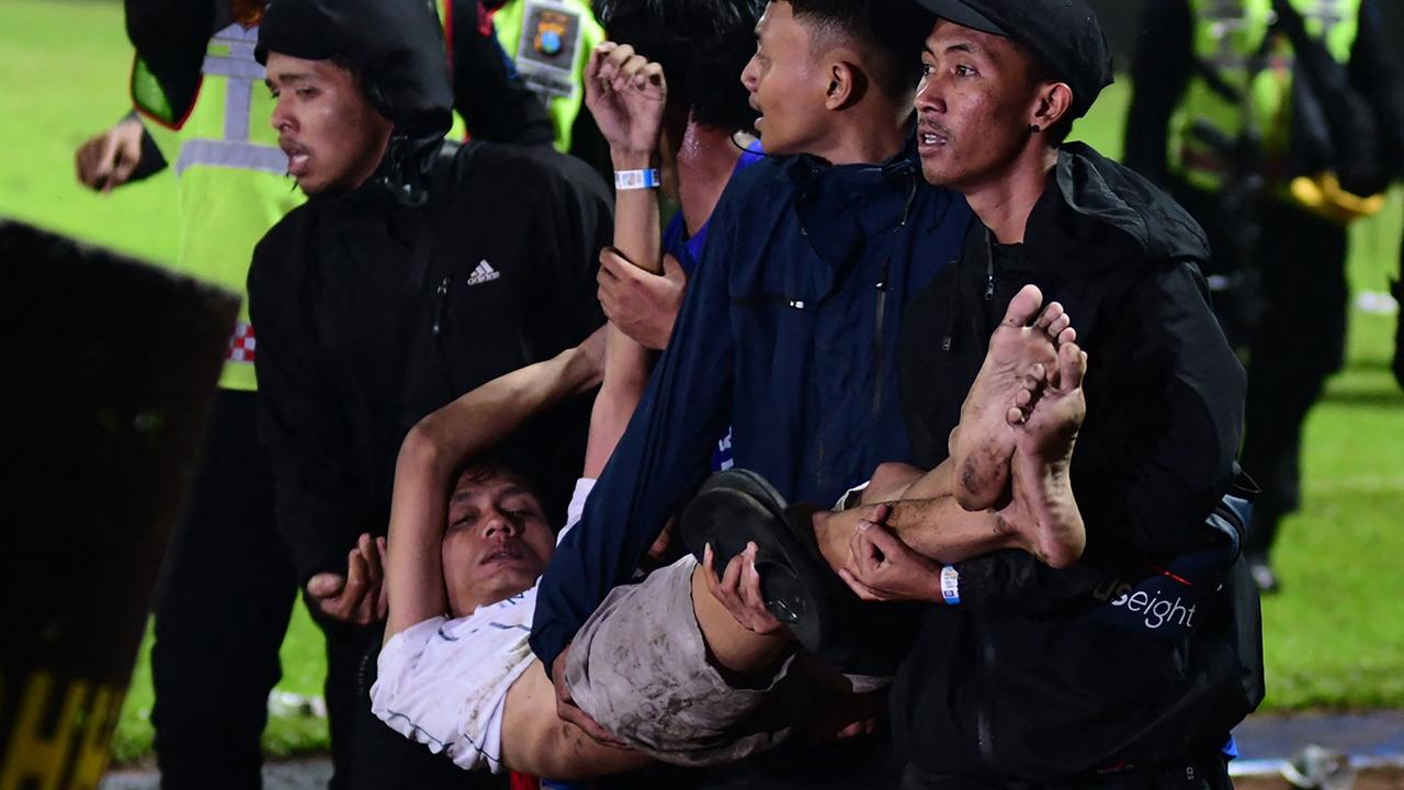 A group of people carry a man at Kanjuruhan Stadium in Malang, East Java. Photo by AFP