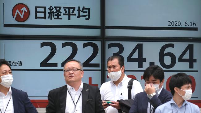 Pedestrians stand in front of an electronic quotation board displaying share prices of the Tokyo Stock Exchange in Tokyo. Picture: Kazuhiro Nogi / AFP.