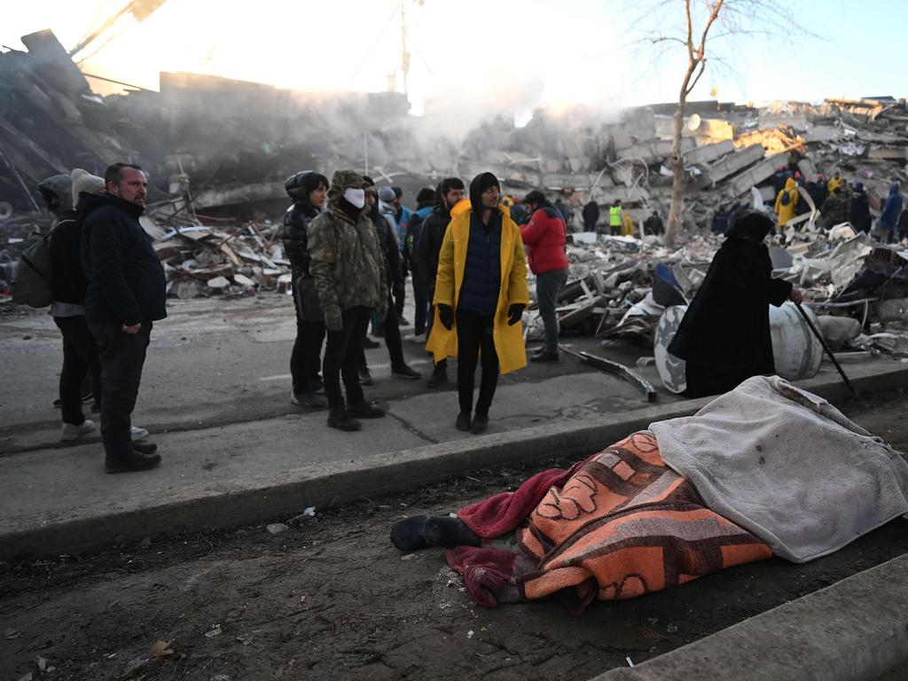 People stand next to victims’ bodies near the rubble of collapsed buildings in Kahramanmaras, Turkey. Picture: AFP