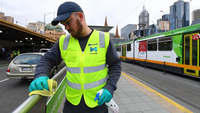 A cleaning team sanitises a Swanston St tram stop. Picture: AAP Image/James Ross