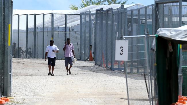 Refugee men at the Nauru compound walk near the entry gate of detention camp 2.