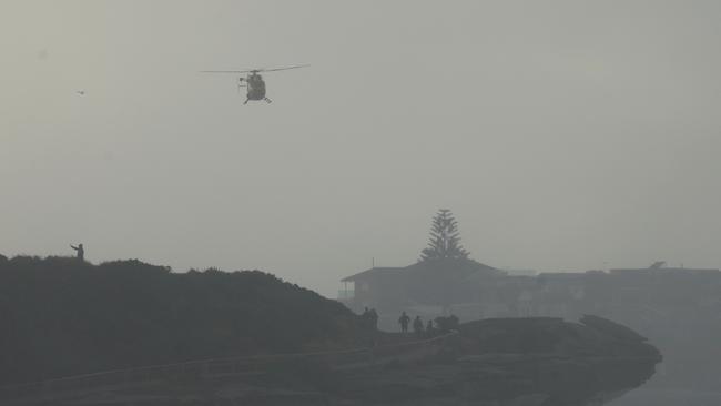 A helicopter searches north of Coogee for an alleged missing surfer early on Wednesday. Picture: John Grainger