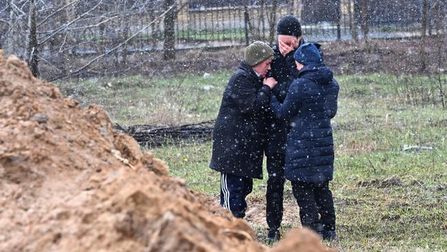 Locals react as they gather close to a mass grave. President Volodymyr Zelensky accused Russia of committing genocide and attempting to eliminate the "whole nation" of Ukraine, a day after the discovery of mass graves and apparently executed civilians near Kyiv.