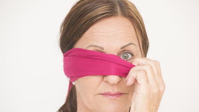 Portrait attractive mature woman with blindfold covering one eye and looking with straight confident view into camera, isolated on white background.