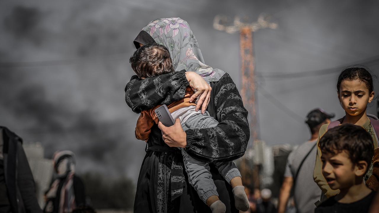 A mother covers her child's face to protect from the smoke as Palestinians leave from the northern part of the Gaza to flee the central and southern parts of the Gaza Strip. Picture: Belal Khaled/Anadolu via Getty Images.