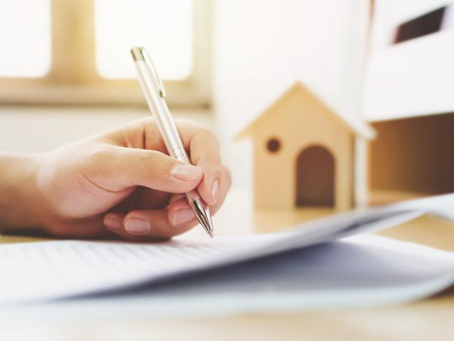 Close up hand of man signing signature loan document to home ownership. Mortgage and real estate property investment