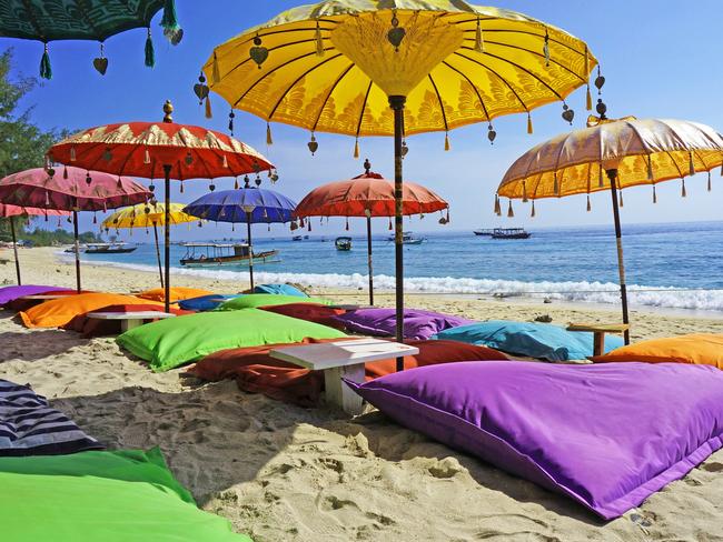 This image shows some colourful beach umbrellas and sand pillows in a pristine tropical beach bathed by the Bali sea.Escape 2 June 2024Kendall HillPhoto - iStock