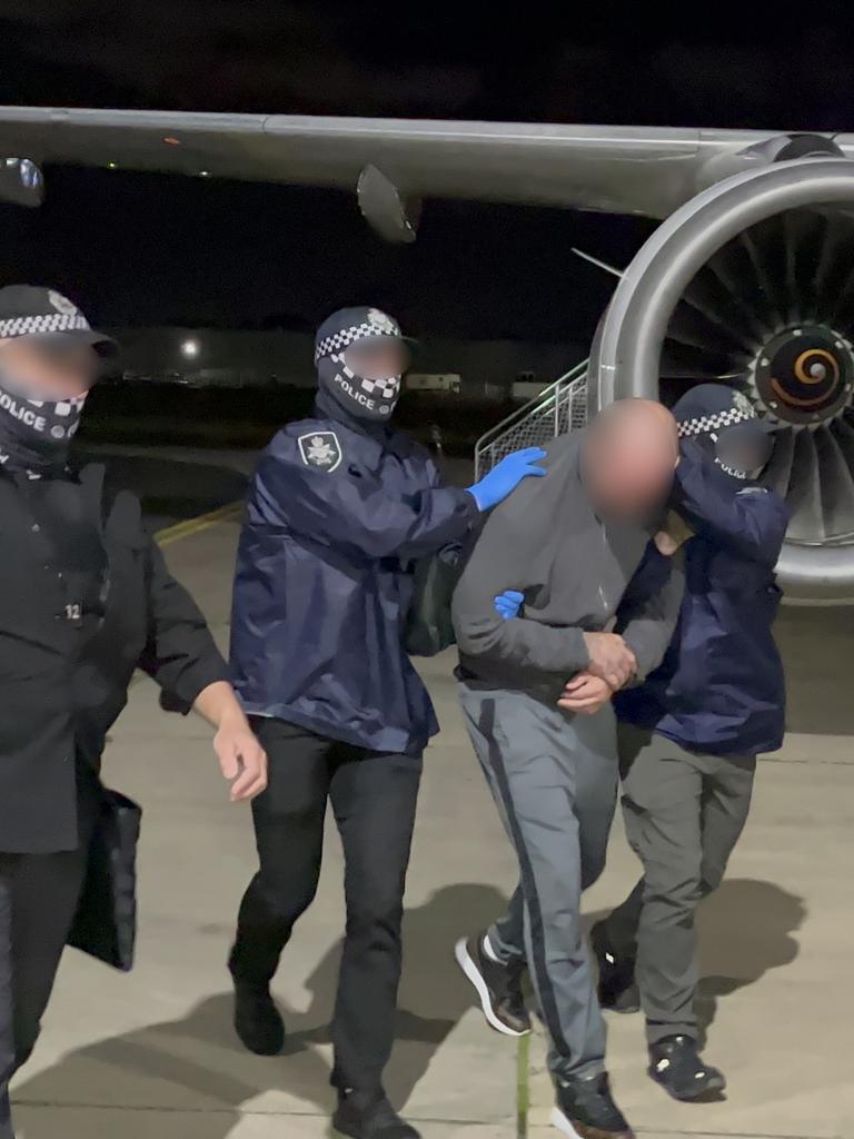 Police bundling Buddle onto the plane in Darwin.