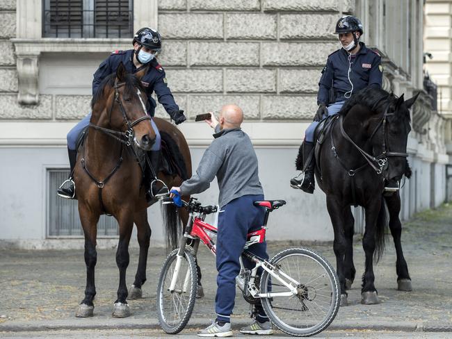 Italian police talk to a cyclist in Rome. The country remains in complete lockdown. Picture: AP