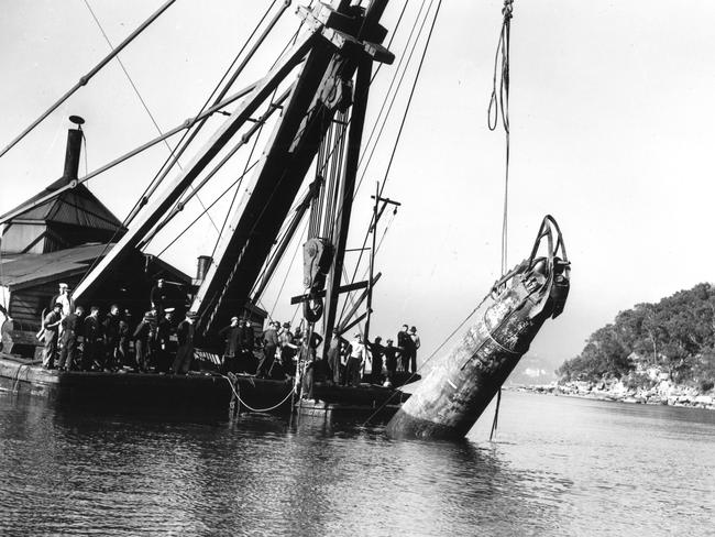 Japanese midget submarine No.21, which took part in a raid in Sydney Harbour in 1942, being raised by a floating crane during a salvage operation. Picture: Australian War Memorial