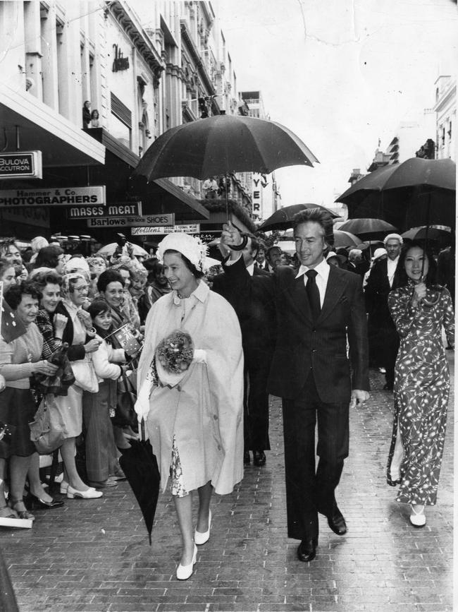 SA Premier Don Dunstan with his wife Adele Koh, holding umbrella over the Queen when light rain fell during her 10-minute walk along Rundle Mall through a crowd of about 7,000 people.