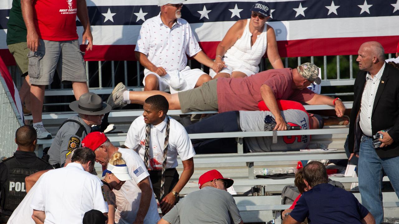 Trump supporters are seen laying in the stands after the shooting.