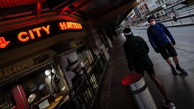 People wearing masks walk past closed shops on Wednesday. Picture: Darrian Traynor/Getty Images