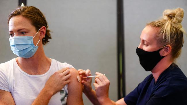 Three time Olympian Australian swimmer Cate Campbell (L) receives her dose of Pfizer/BioNTech vaccine against Covid-19 at the Queensland Sports and Athletics Centre in Brisbane on May 10, 2021, after the Australian Olympic Committee began their rollout of vaccinations for members of the Olympic team ahead of the the games in Tokyo. (Photo by Patrick HAMILTON / AFP)